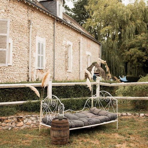 Lit de repos en fer devant la maison en pierre du domaine