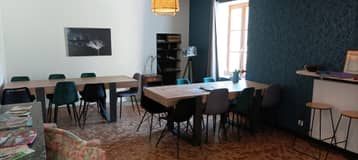 Salon de l'auberge, table et chaises devant un mur bleu