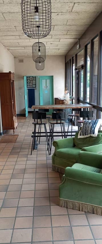 Espace de travail de la salle de la colonie, tables hautes et fauteuils verts