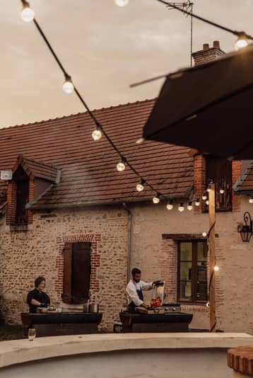 Cour du domaine sous des guirlandes lumineuses, à la tombée du jour