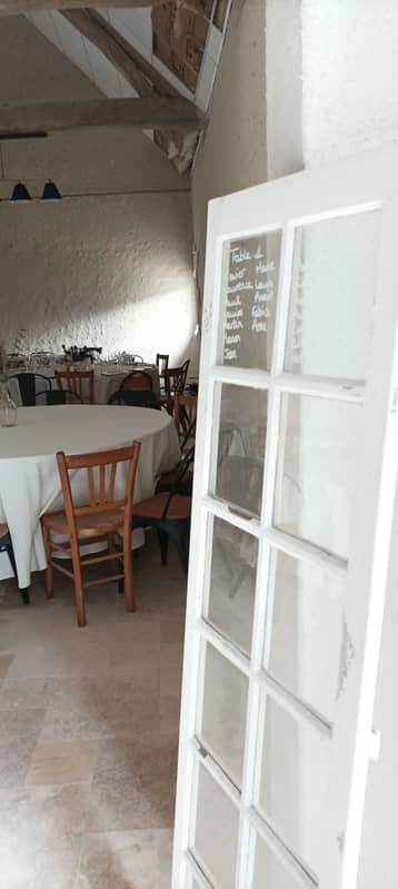 Porte vitrée donnant sur la salle de la grange, table ronde dressée