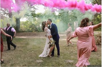 Mariés qui s'embrassent dans un nuage de fumée rose