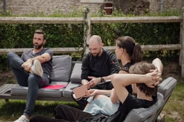 Équipe en pause sur des canapés d'extérieur, dans le jardin