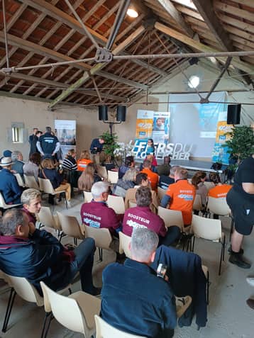 Grange aménagée pour un séminaire, longues tables et banderoles devant la scène