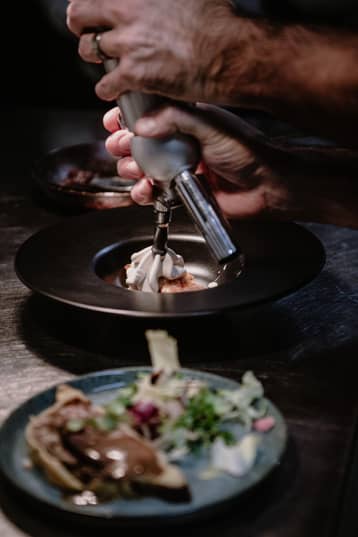 Mains d'un cuisinier garnissant une assiette