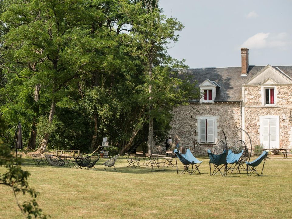 Cour du manoir, façade en pierre et transats sur la pelouse