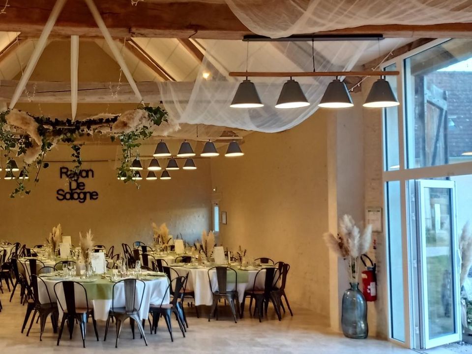 Grange décorée de voilages et de guirlandes, tables dressées
