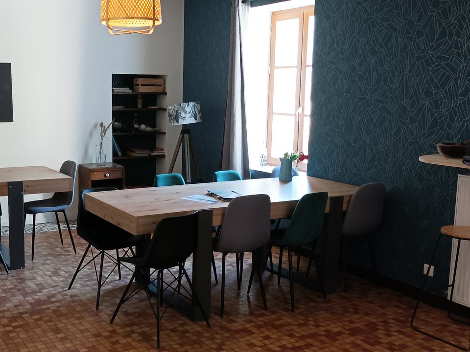 Salon de l'auberge, table et chaises devant un mur bleu