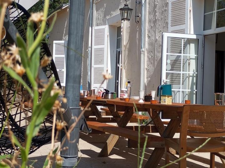 Terrasse du gîte XXL du manoir, table de pique-nique en bois et volets blancs