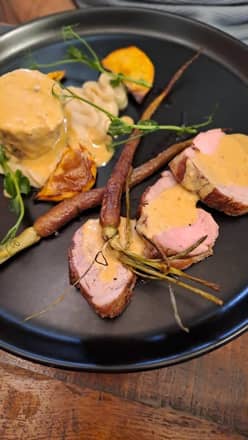 Plat de viande rosée et carottes dans une assiette noire