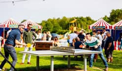 Partie de ping-pong en extérieur lors d'une soirée, tentes rayées au fond