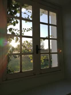 Fenêtre à petits carreaux de la chambre des mariés, soleil à travers le feuillage